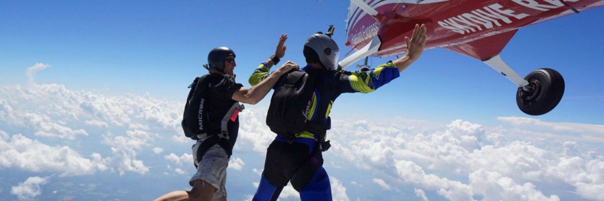 student exits plane alongside skydiving instructor