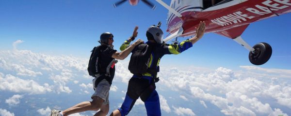 student exits plane alongside skydiving instructor