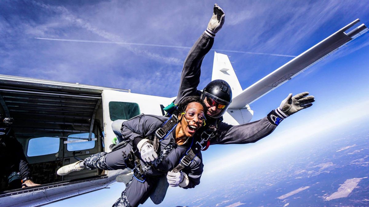 African American tandem skydiver exits airplane 