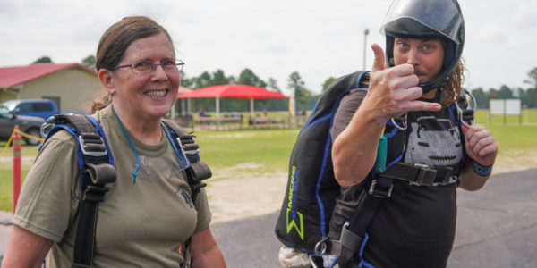 Tandem student and instructor walk toward plane to go skydiving