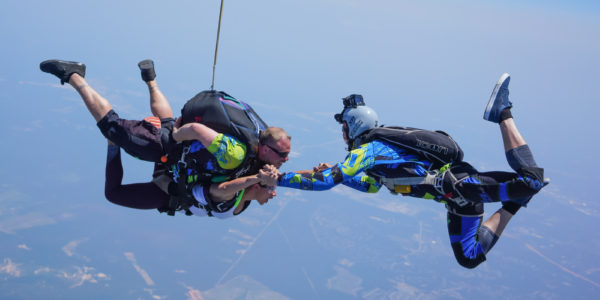 Tandem skydivers in freefall with videographer