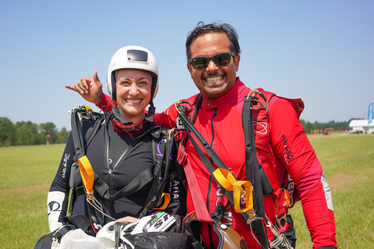 an instructor and a student skydiver smile on the ground after a skydive