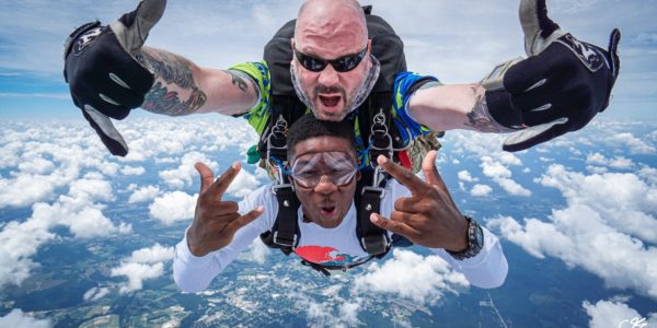 A male pair rocking out a tandem skydive.
