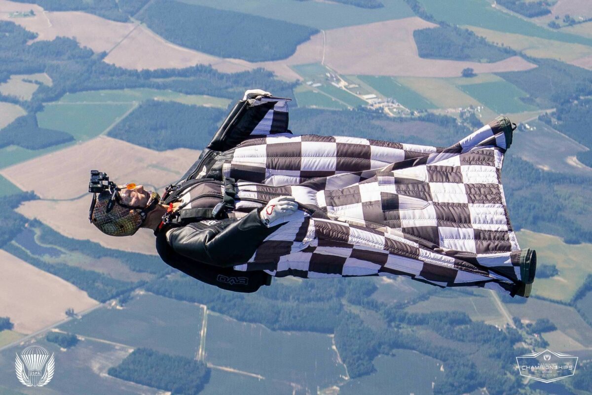 A wingsuiter in a black and white checkered wingsuit flies on his back at the USPA Nationals. Photo by Chris Bess.