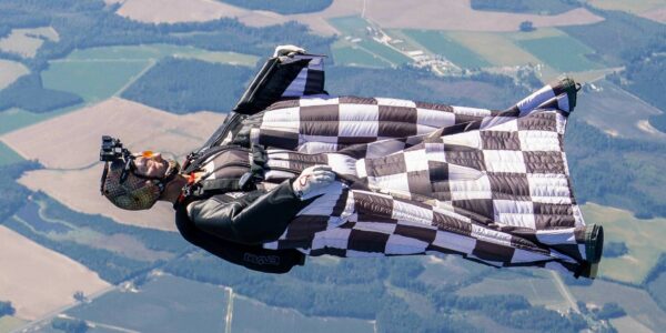A wingsuiter in a black and white checkered wingsuit flies on his back at the USPA Nationals. Photo by Chris Bess.