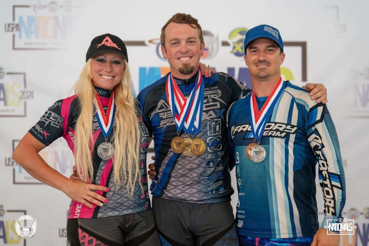 Three skydivers standing on podium with medals 